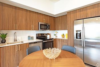 A modern kitchen with wooden cabinets and stainless steel appliances from our model 2-bedroom at Hollywood Heights on the Boulevard Luxury Apartments in Hollywood, FL.